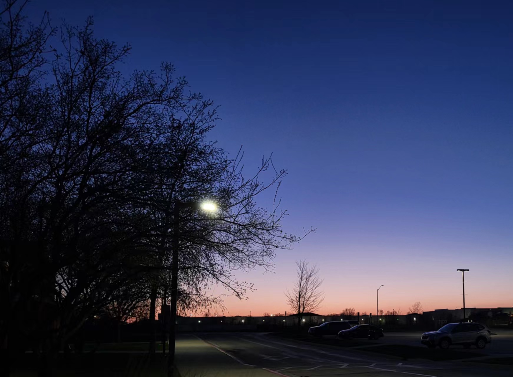 A gorgeous sunset picture with deep purple colors, taken in a parking lot.